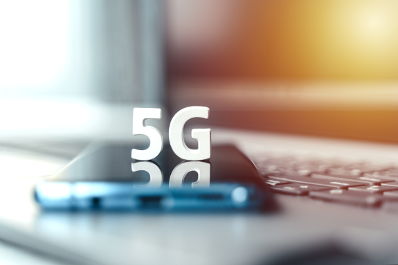 5G text on smartphone screen with laptop keyboard background