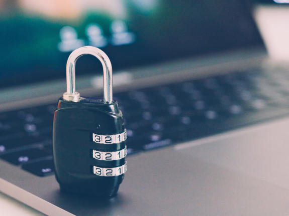 Combination lock sitting on a laptop keyboard, symbolizing cybersecurity.
